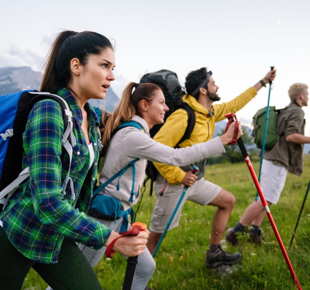 Group of friends trekking with backpacks walking in the forest