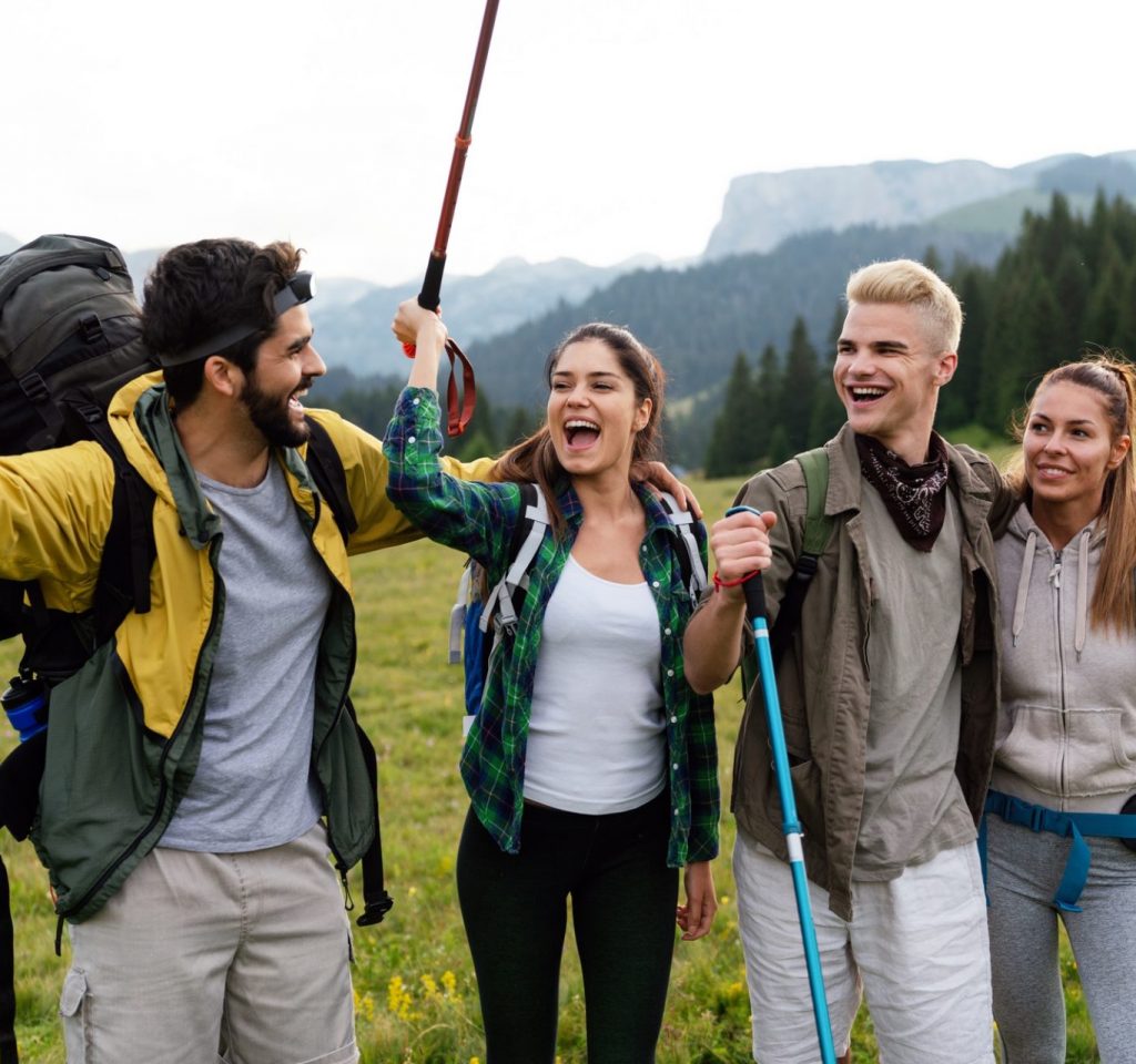 Group of friends trekking with backpacks walking in the forest